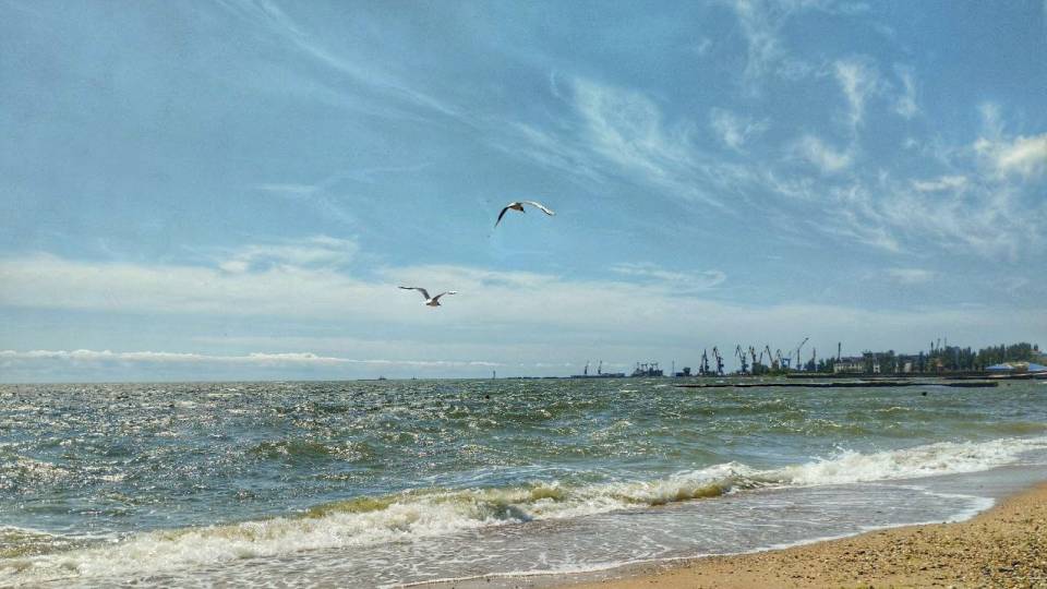 Берег Азовського моря в Маріуполі. На фоні видно зруйнований комбінат 